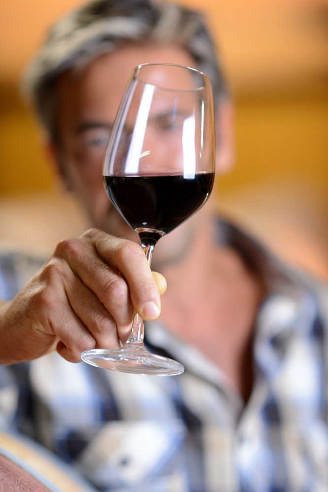 Focus on glass of red wine hold by winemaker-1